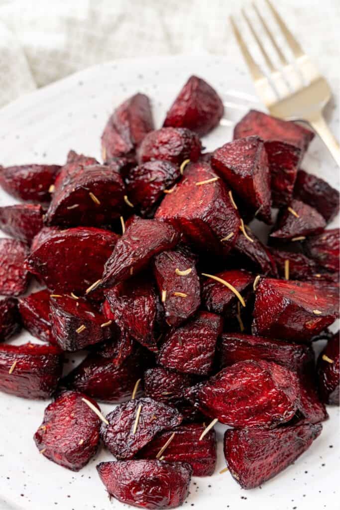 Close up of air fryer beets on a white plate with a fork.