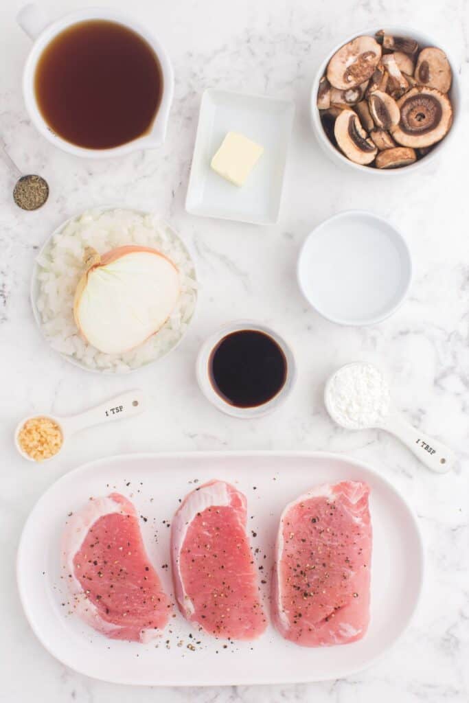 Ingredients needed to make pork chops in the Instant Pot: boneless pork chops, salt, pepper, butter, onion, mushrooms, garlic, beef broth, thyme, cornstarch, and water.