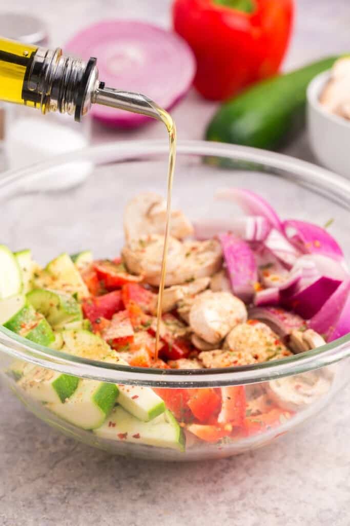 pouring olive oil over raw vegetables