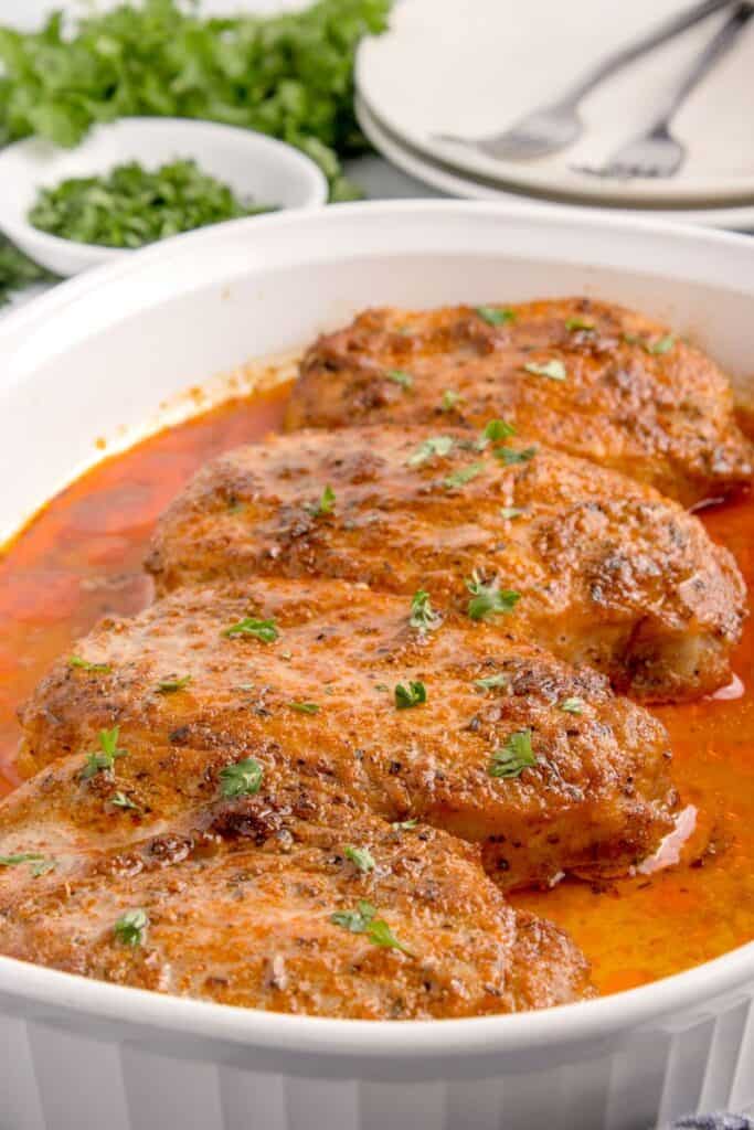 baked pork chops in a white baking dish 
