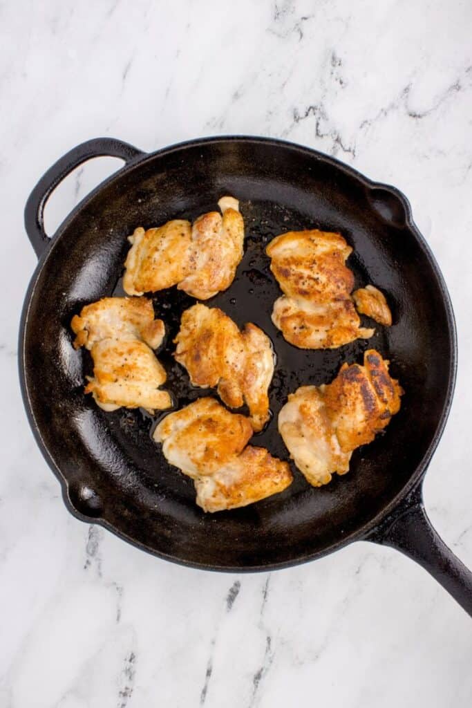 seared chicken thighs in a black cast iron skillet