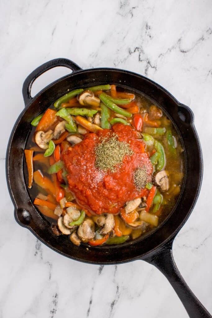 adding tomatoes and chicken broth to the veggies