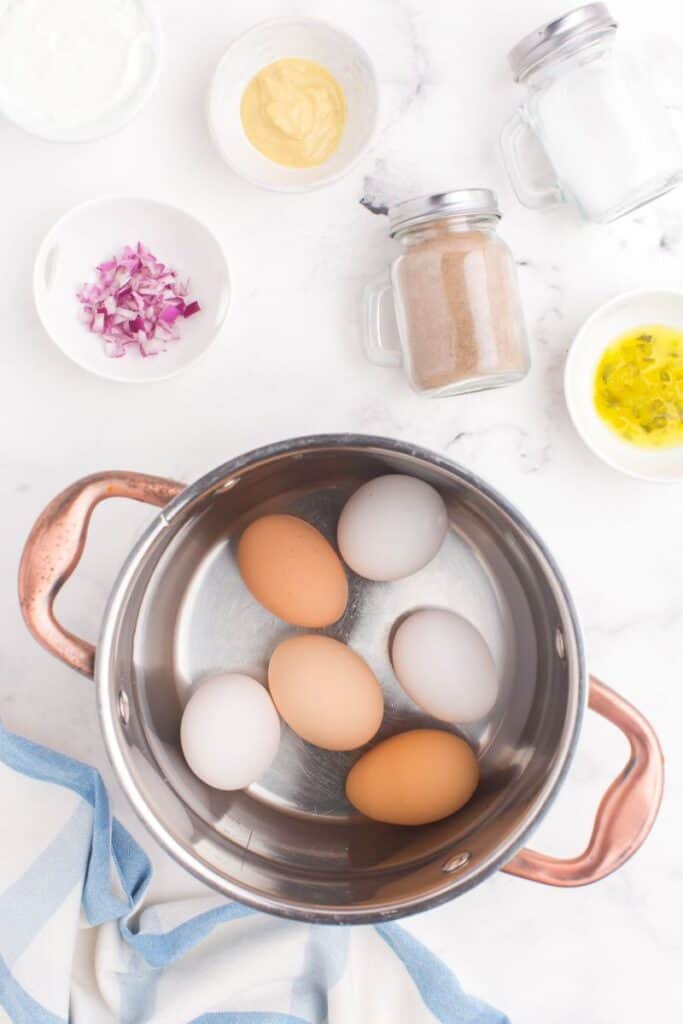 adding eggs to cool water in a large pot.