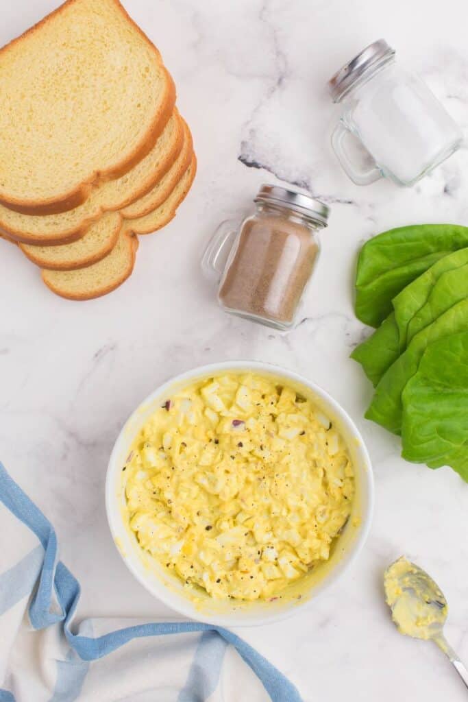 mixing egg salad mixture in a white bowl