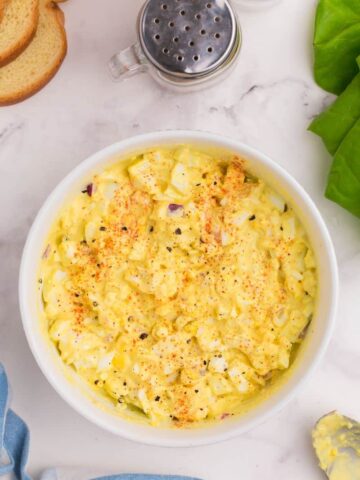 overhead shot of egg salad in a bowl seasoned with black pepper and paprika.