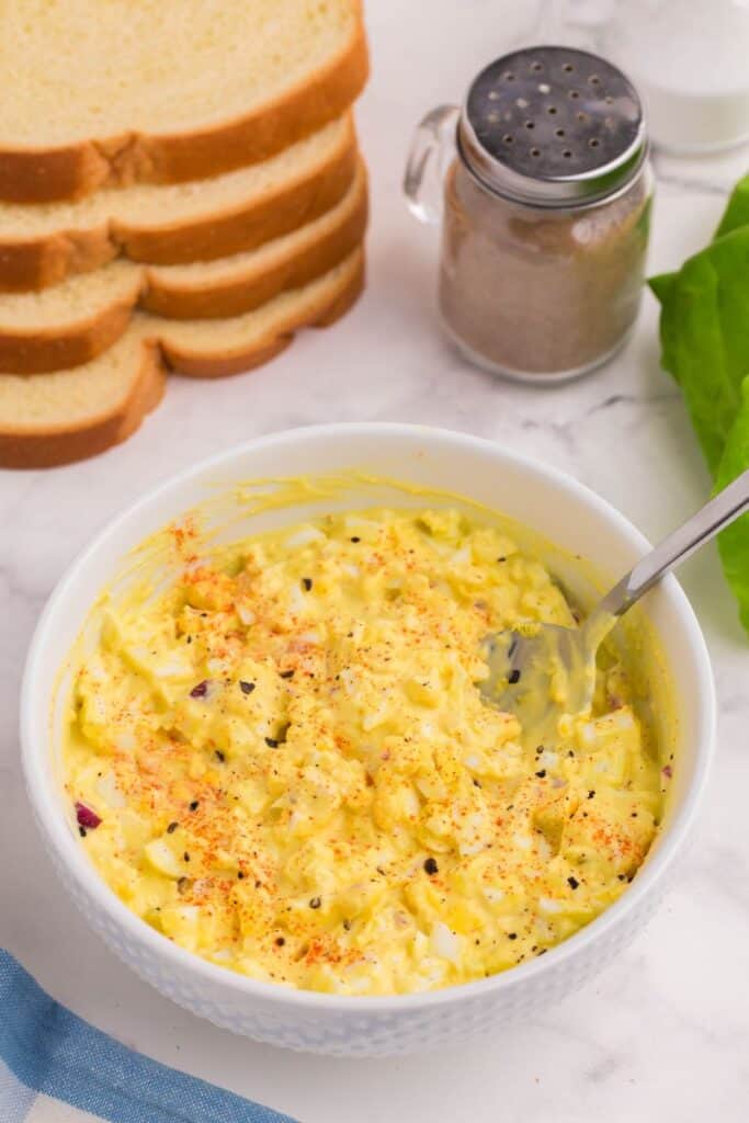 a bowl of traditional egg salad with a silver serving spoon