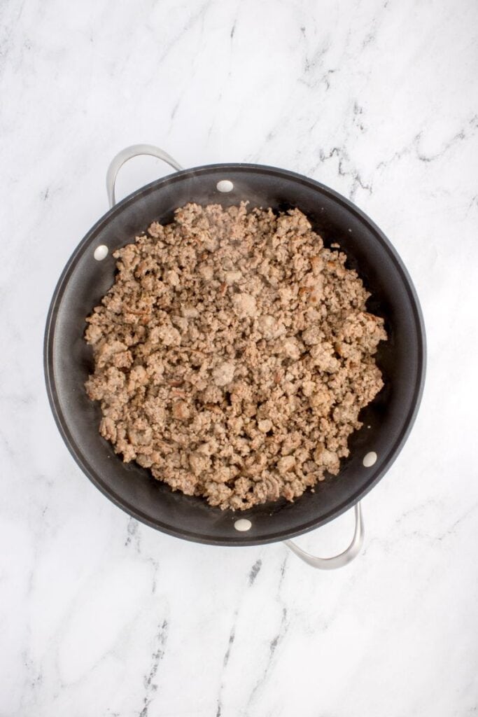 cooking ground beef and ground sausage in a black pan.