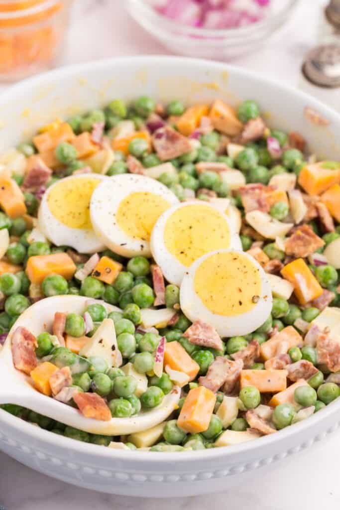 peas, cheese, onions and hard boiled eggs dressed in a bowl 
