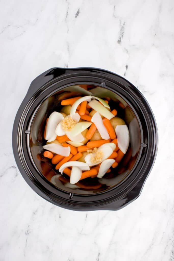onions, potatoes, carrots and garlic in slow cooker