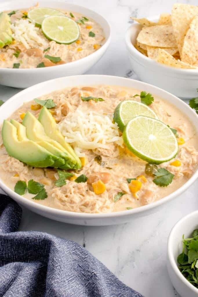 bowl of cheesy chicken chili with avocado and lime slices