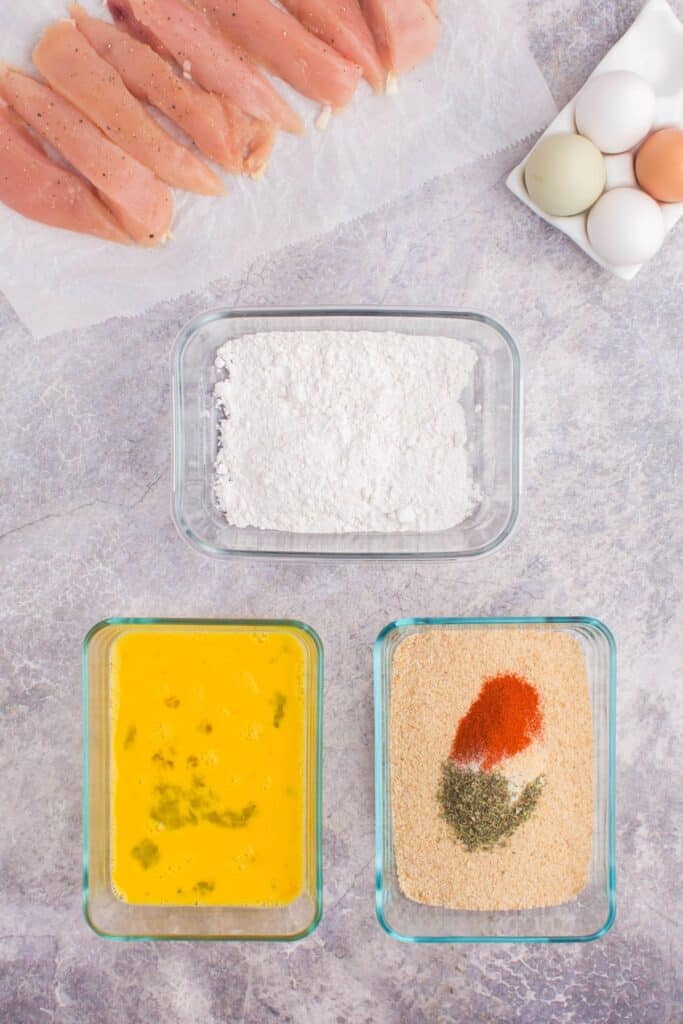 overview of egg in a bowl and seasonings with breadcrumbs in a bowl.