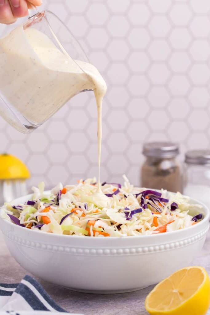 drizzling coleslaw dressing over cabbage mix