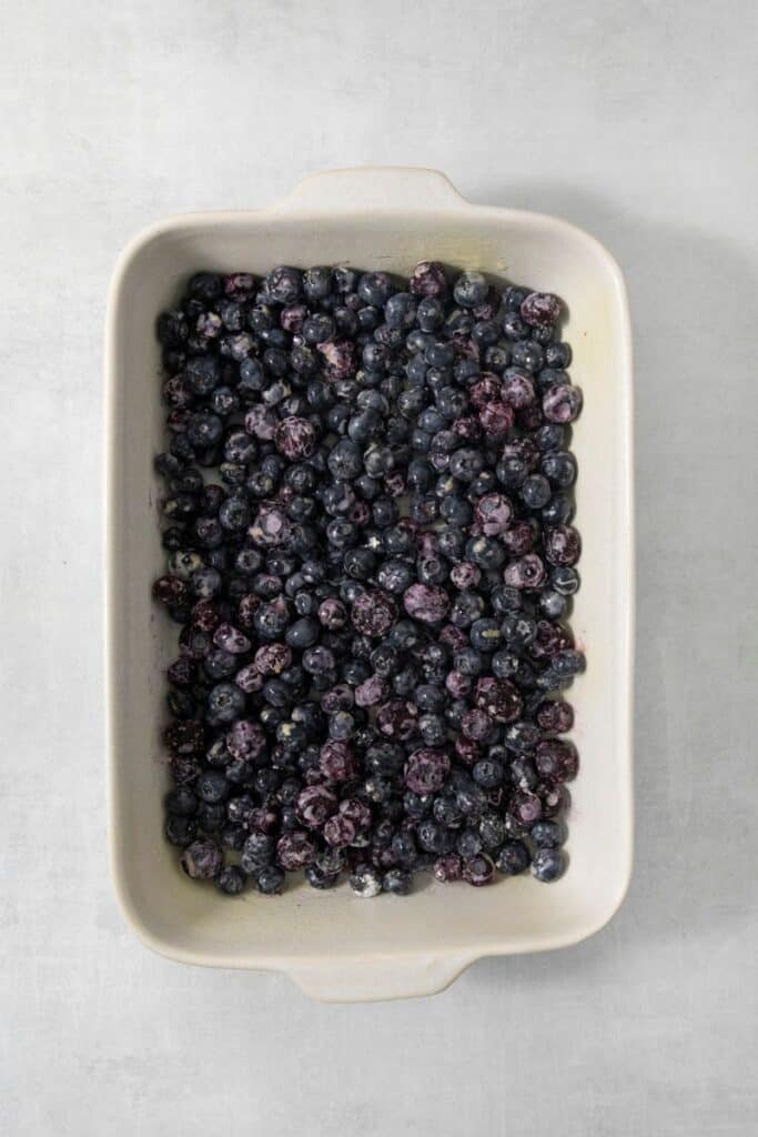 adding blueberries to a baking dish