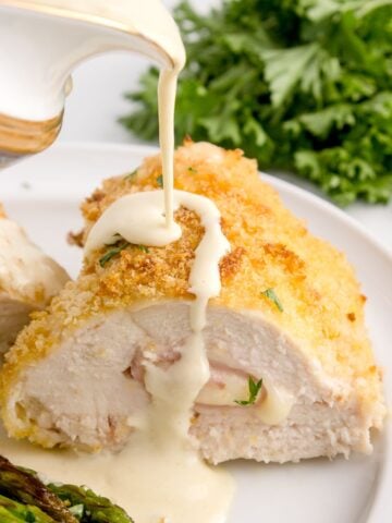 drizzling creamy dijon sauce over the stuffed chicken
