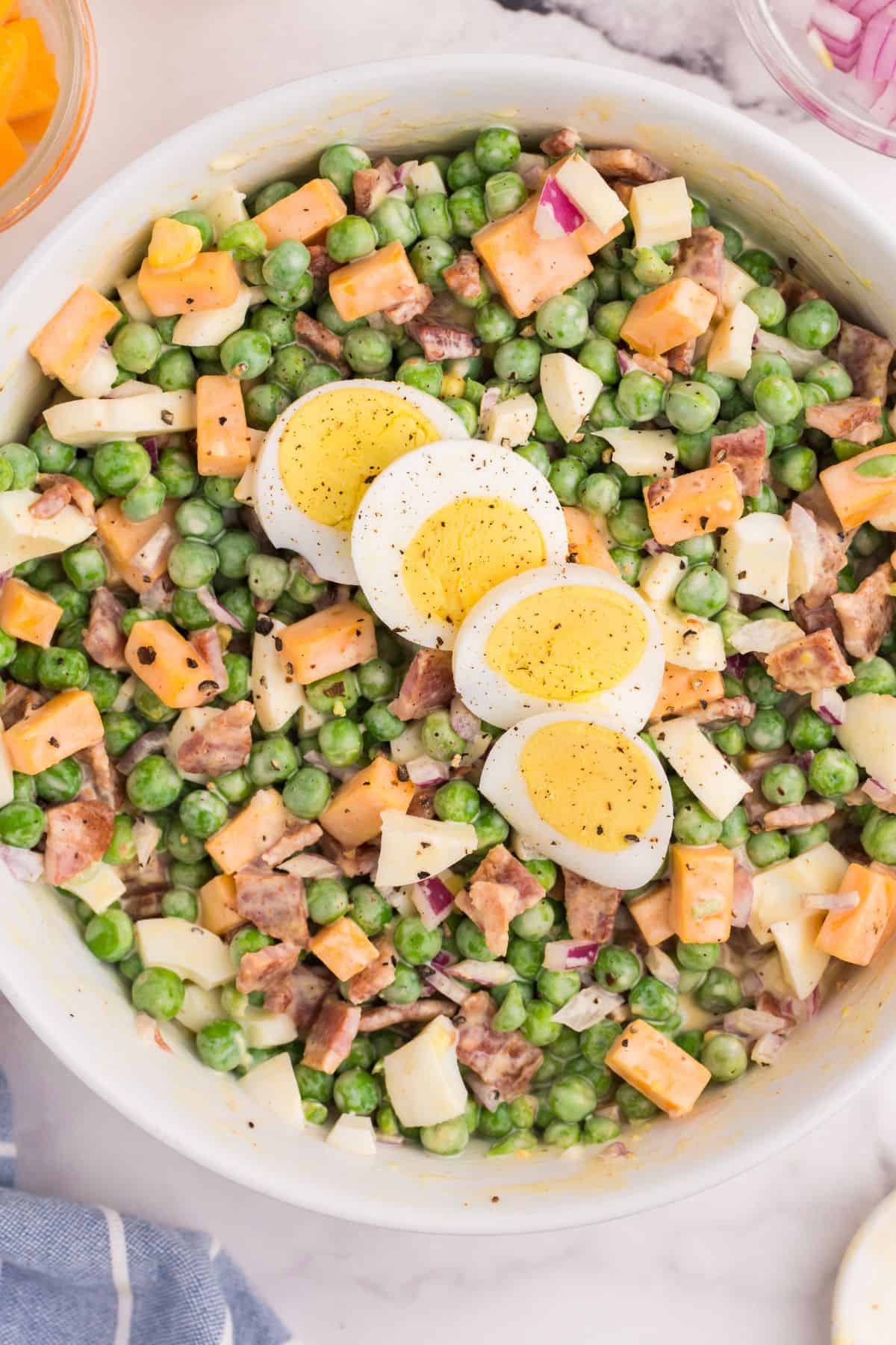 Overhead view of pea salad with eggs on top of it.