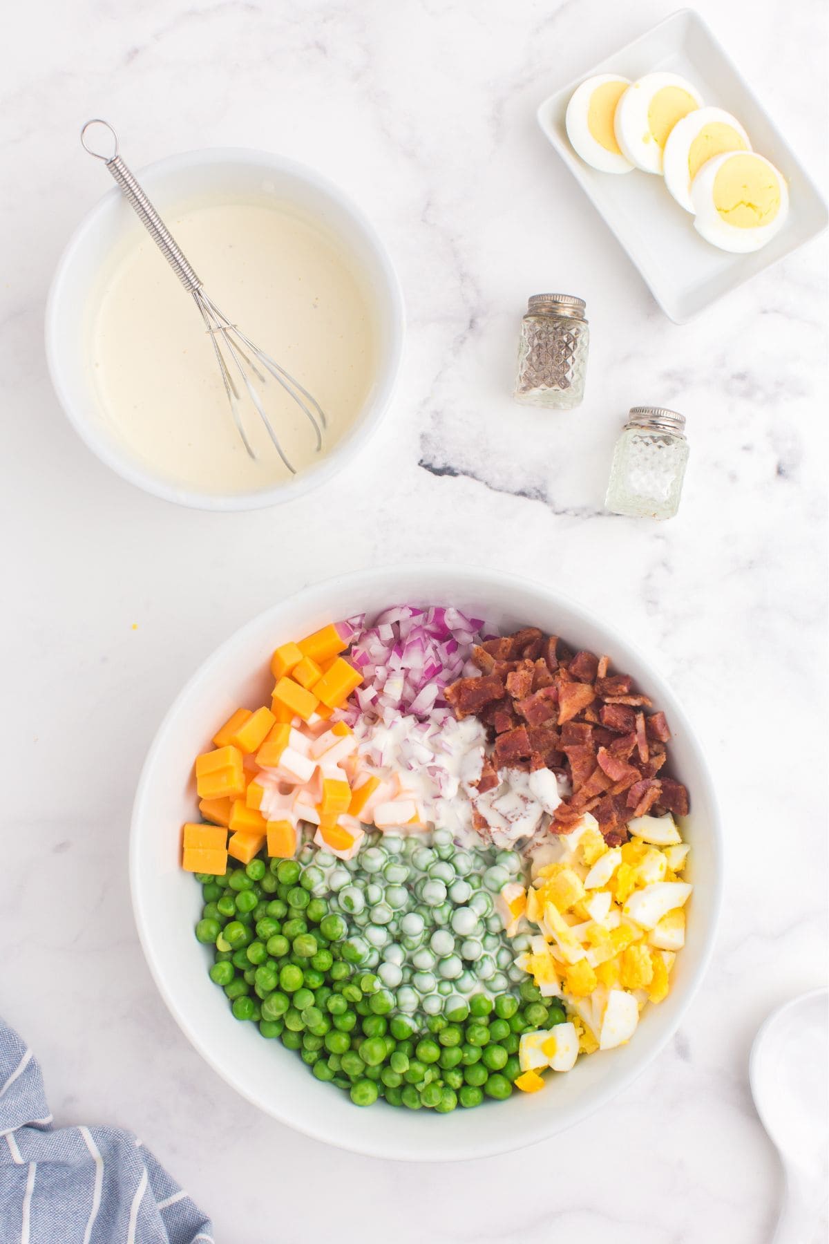 Creamy mixture being mixed into the pea salad recipe ingredients.