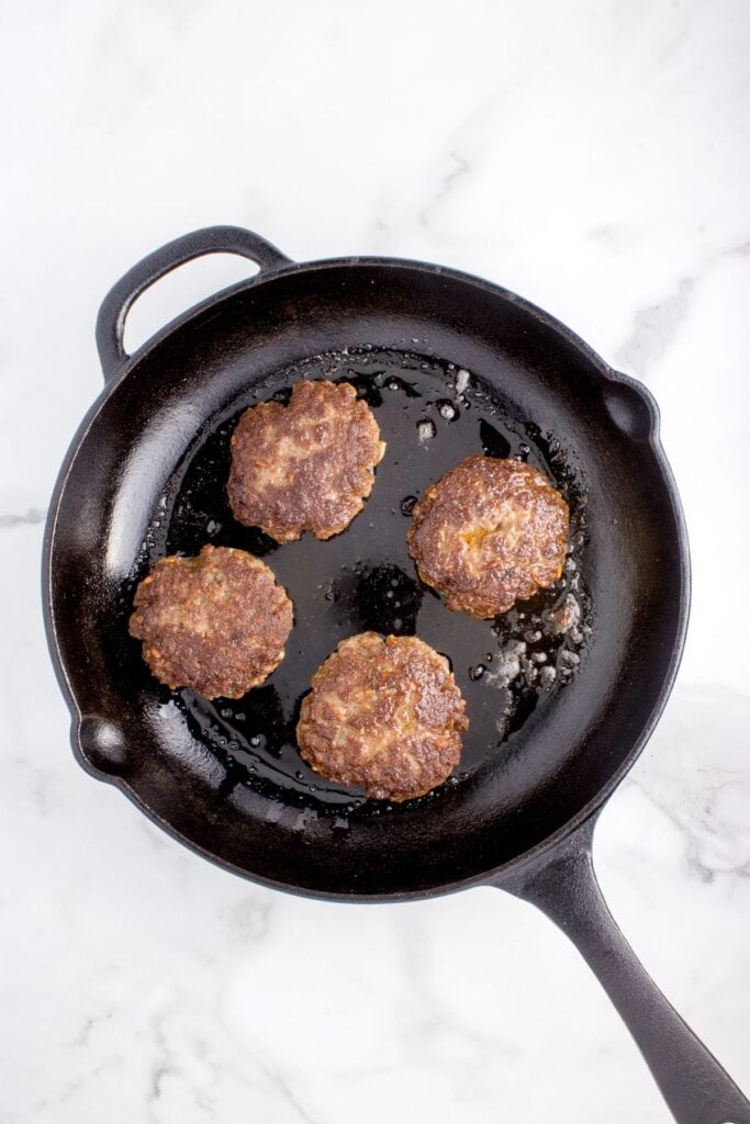 seared ground beef patties with in a cast iron skillet
