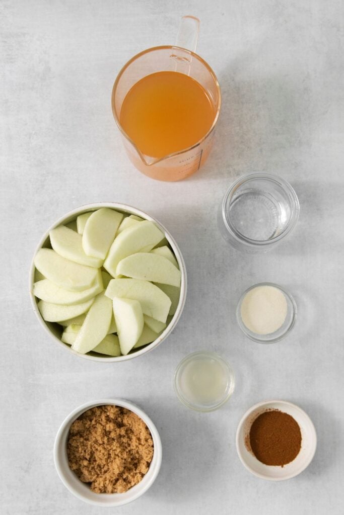 Ingredients needed to make an apple pie in a graham cracker crust: graham crackers, sugar, butter, honey, water, gelatin, apple cider, apples, brown sugar, lemon juice, apple pie spice, almond flour, oats, and cinnamon.