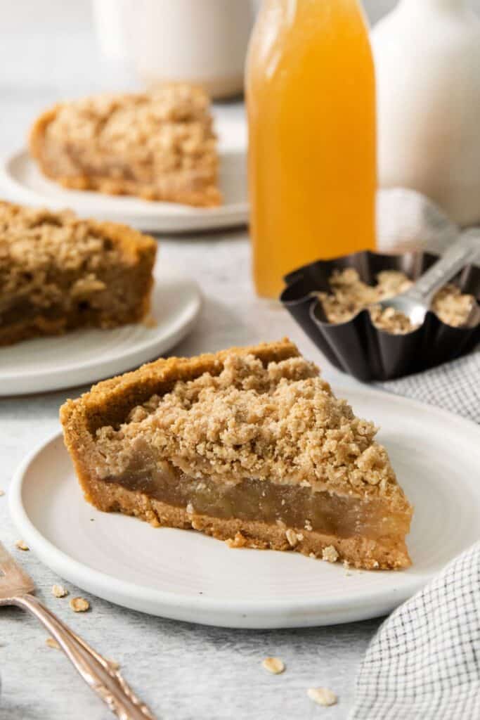 Apple pie with graham cracker crust slice on a white plate so you can inside it.