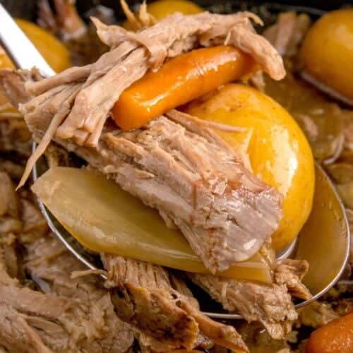 Close up of the sirloin tip roast in the crock pot being picked up with a spoon with carrots and baby potatoes.