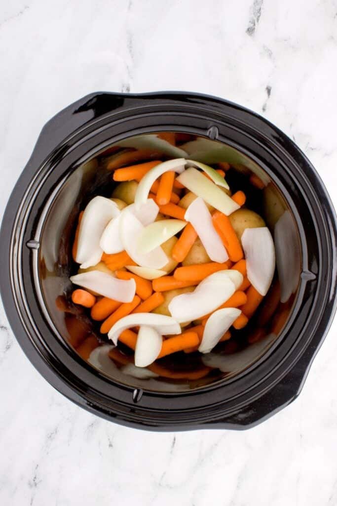 Onions, potatoes, and carrots in the slow cooker.