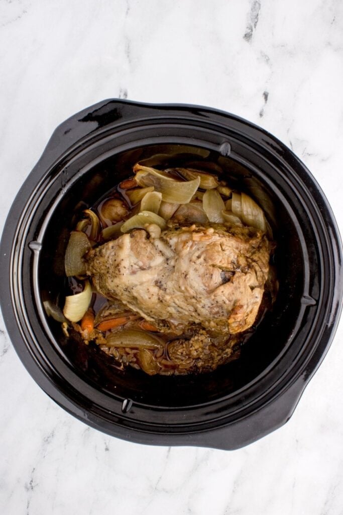 Cooked slow cooker sirloin tip roast with the beef on top and veggies underneath.