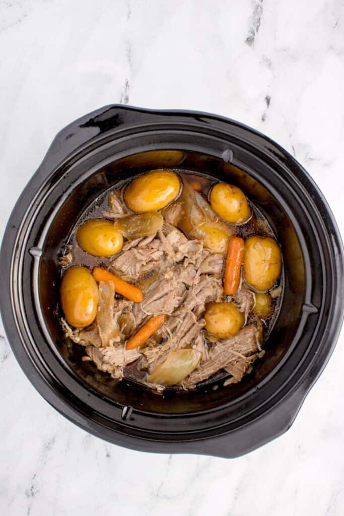 Cooked sirloin tip roast in the slow cooker with the beef shredded.