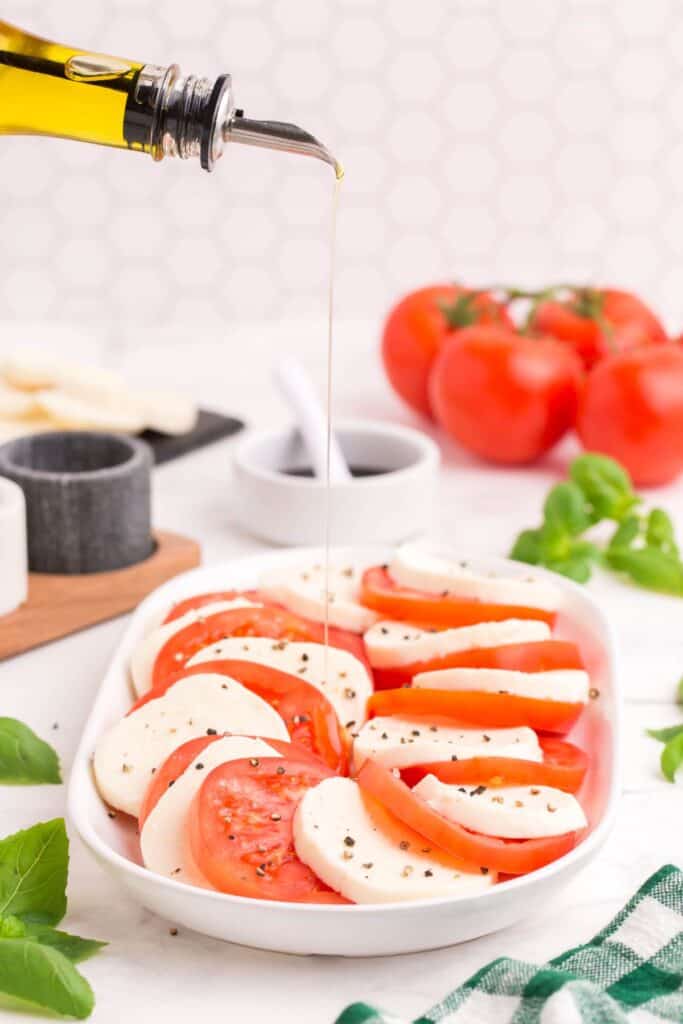 drizzle mozzarella caprese salad with olive oil and season with salt and pepper