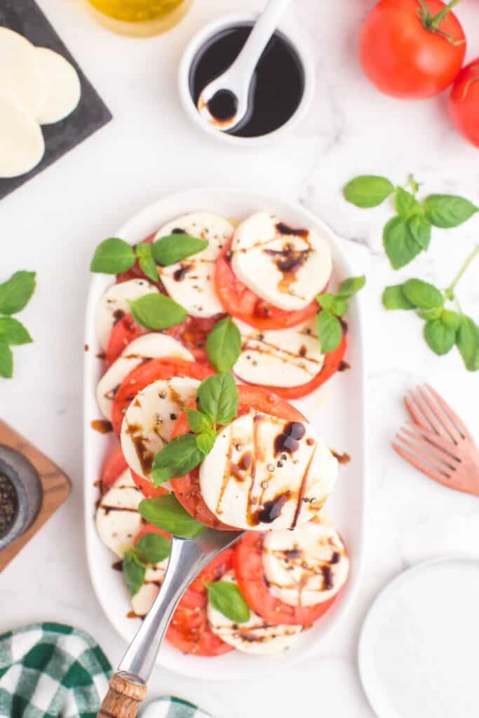 serving mozzarella and tomato salad with fresh basil leaves