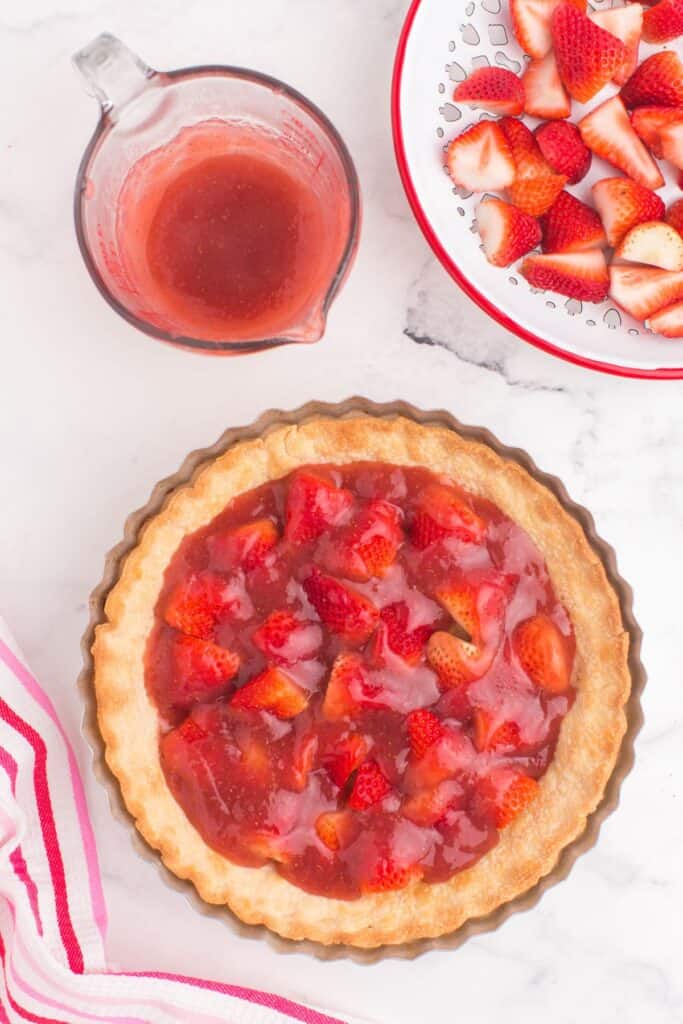 layering fresh strawberries and strawberry filling in a pie crust 