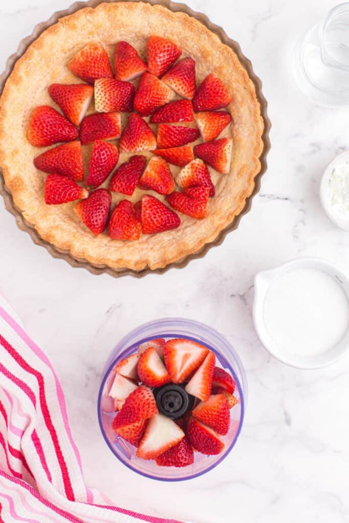 adding sliced strawberries to a food processor