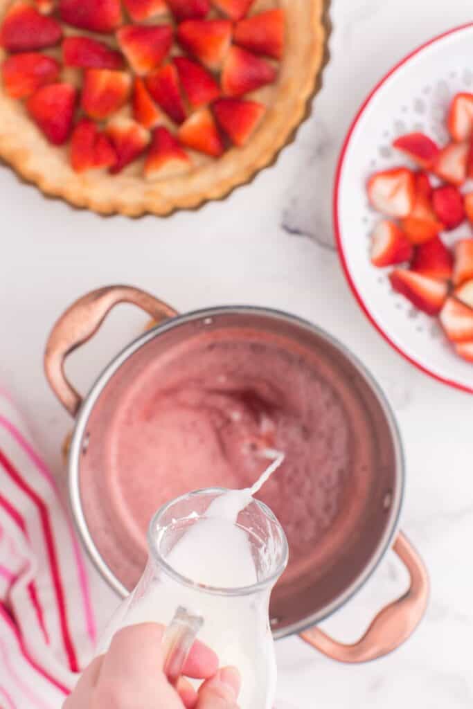 adding a cornstarch slurry to blended strawberries and sugar