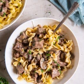 Beef Stroganoff in a bowl with a fork served with egg noodles