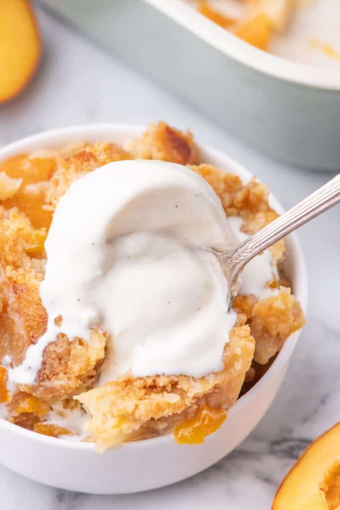 eating a bite of peach dump cake pie with melted vanilla ice cream 