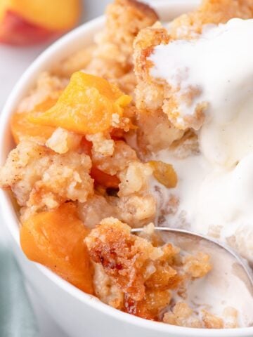 close up of peach cobbler cake with ice cream and peach chunks