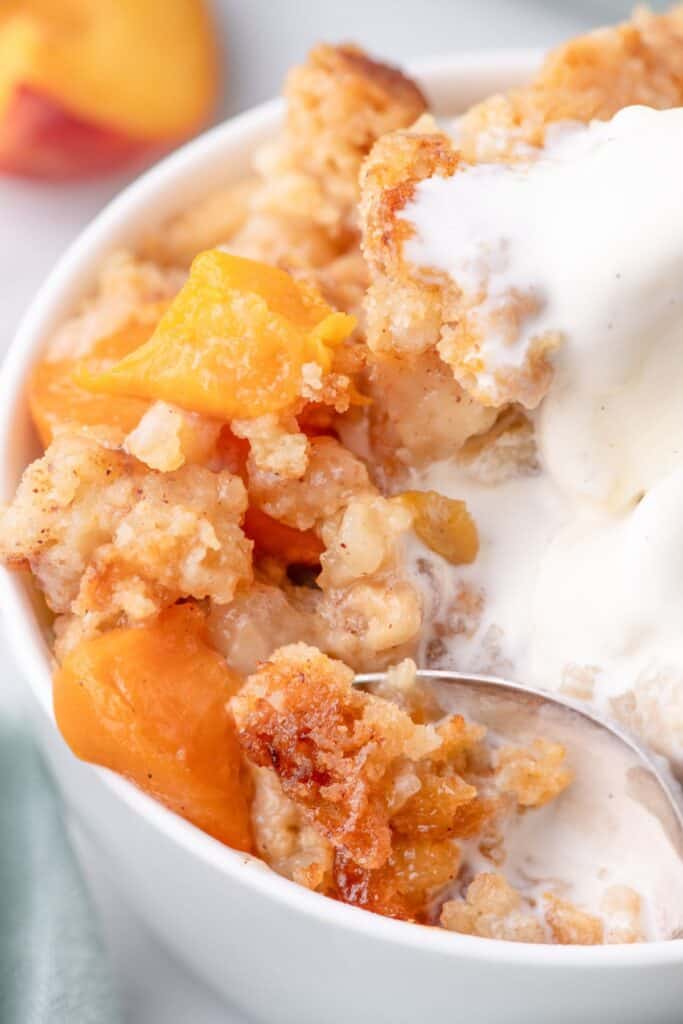 close up of peach cobbler cake with ice cream and peach chunks 