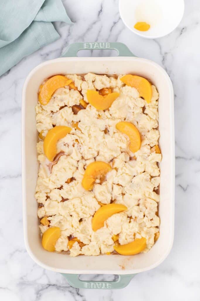 adding drained sliced peaches over the top of cake mix