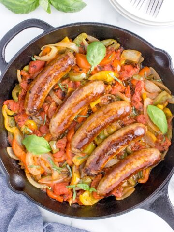 overhead shot of italian sausage, peppers and onions in a cast iron skillet