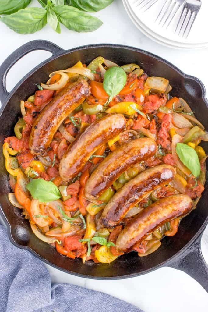 overhead shot of italian sausage, peppers and onions in a cast iron skillet