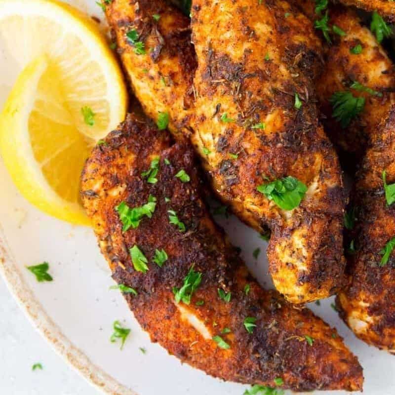 naked air fryer chicken tenders on plate with lemon wedges on side