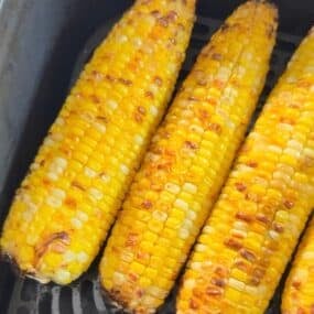 Air fryer corn on the cob cooked inside an air fryer basket.