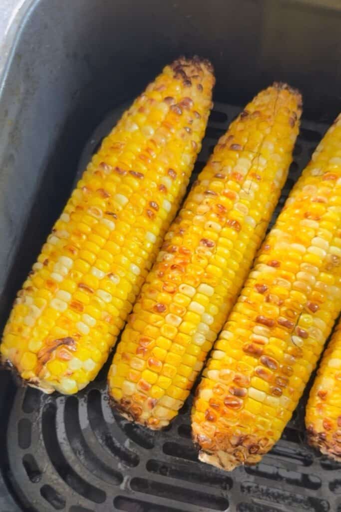 Air fryer corn on the cob cooked inside an air fryer basket.