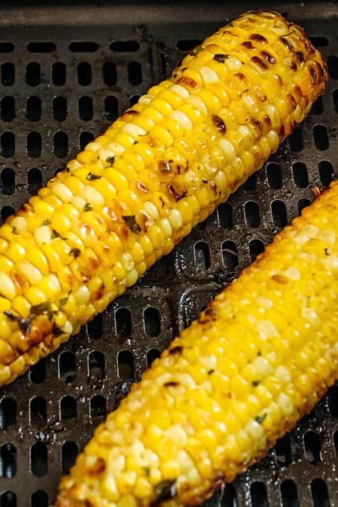 Close up of cooked corn on the cob in an air fryer basket.