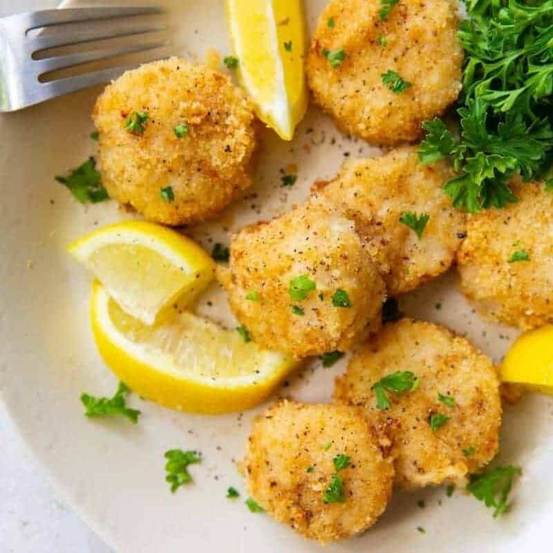 Scallops on a plate with lemon slices and parsley