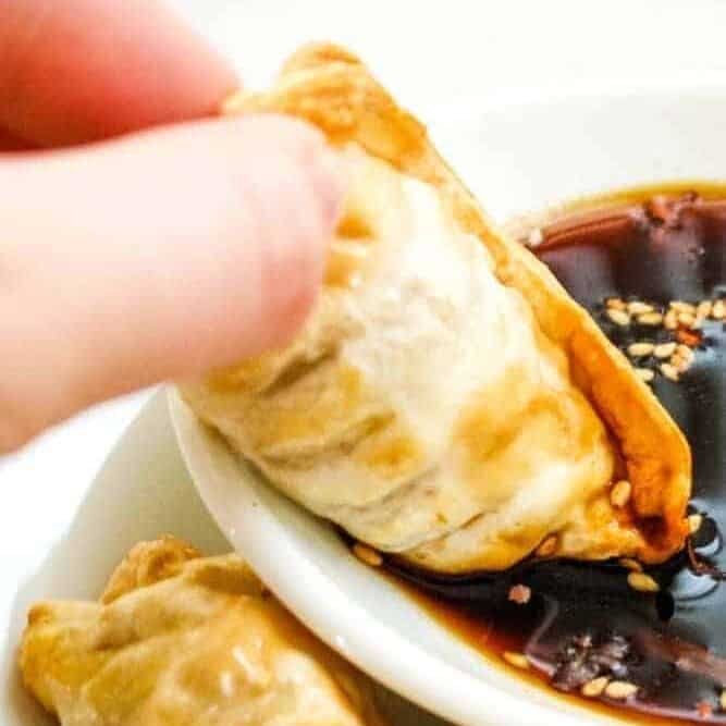 Dipping Air Fryer Dumpling in Sauce on a white plate