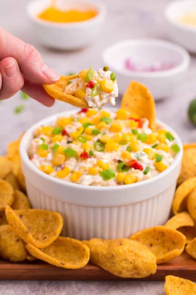 scooping up creamy corn dip with frito chip