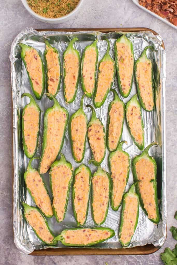 Jalapeno poppers with cream cheese filling in them ready to be baked.