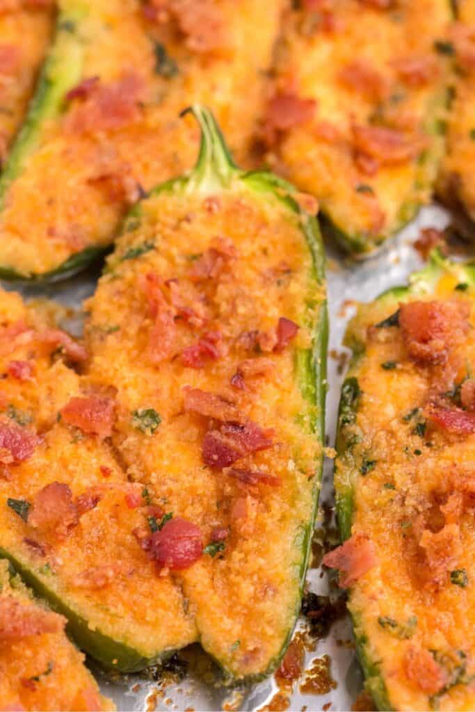 Close up of jalapeno poppers in the oven with bacon on top.