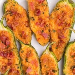 Jalapeno poppers in the oven on a white plate all cooked.