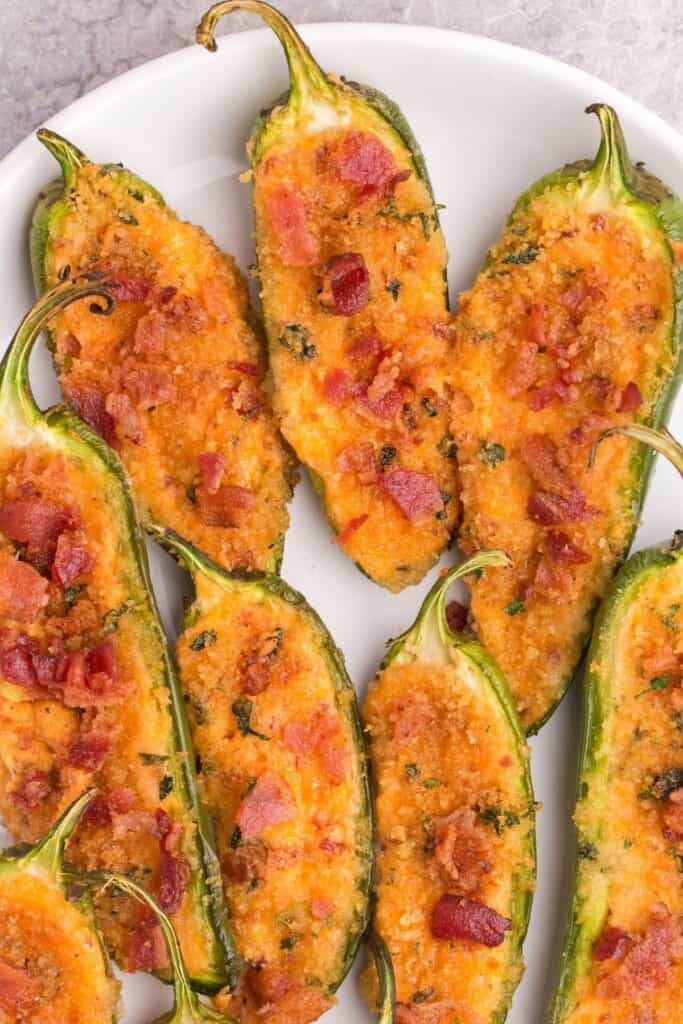 Jalapeno poppers in the oven on a white plate all cooked.